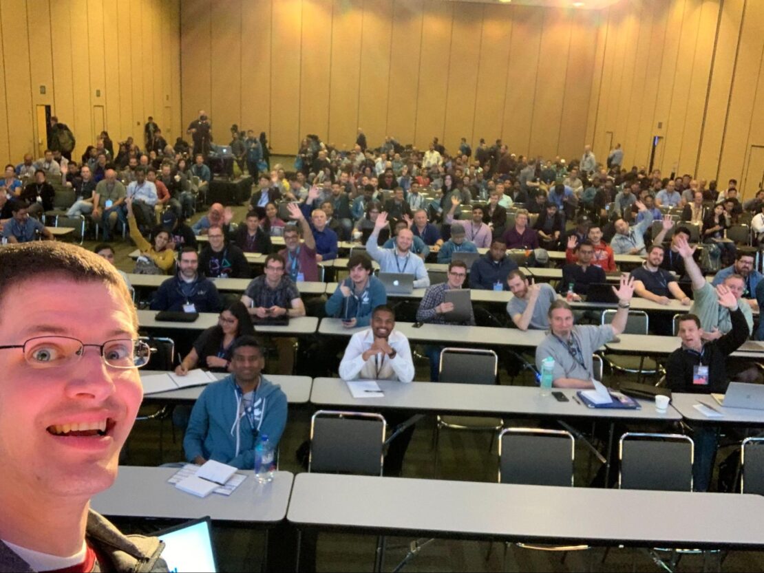 サンフランシスコで開催されたDockercon 2019での「初心者向けコンテナ」トークの前に撮影された、手を振る聴衆の前で笑顔の男性を示すマイケルアーウィンの自撮り写真。